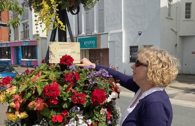 A Barnstaple in Bloom memorial baskets plant stand being watered by a volunteer. Credit: Barnstaple in Bloom