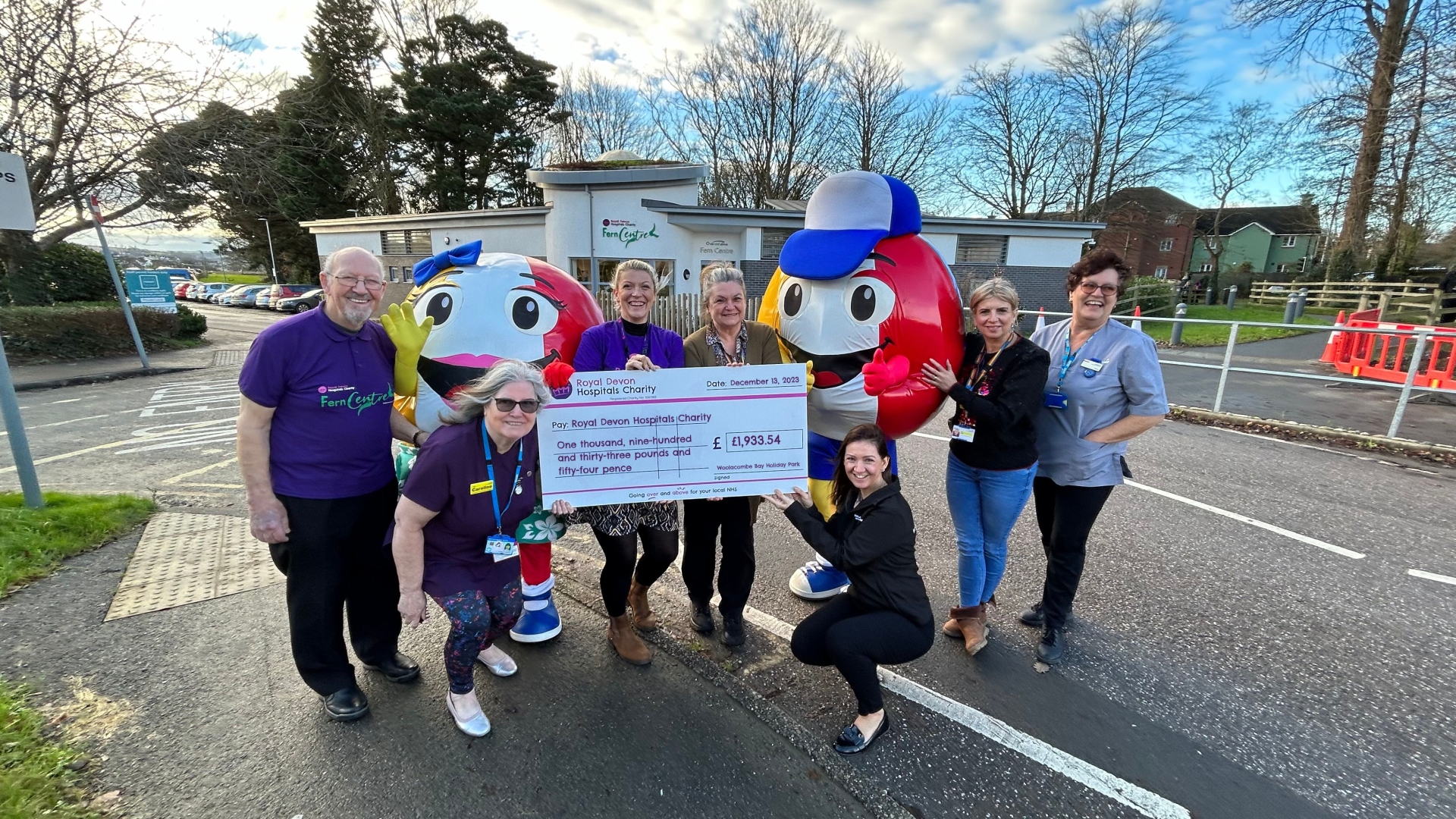 Woolacombe Bay Holiday Parks head of entertainment and HR, Kate Glover and mascots Billy and Betty Beachball, present the cheque to Royal Devon Hospitals Charity community fundraiser Kate Constable an
