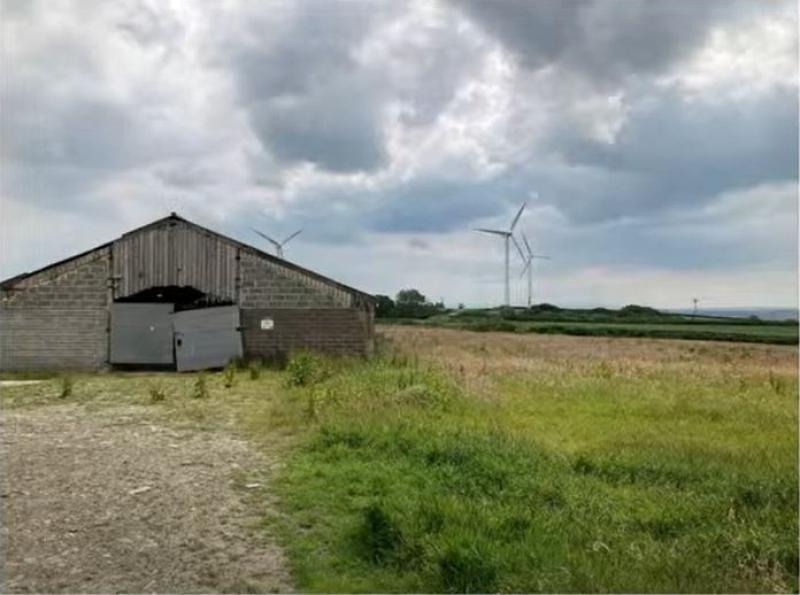 The barn proposed for redevelopment with the wind turbines in the background - Credit: TDC