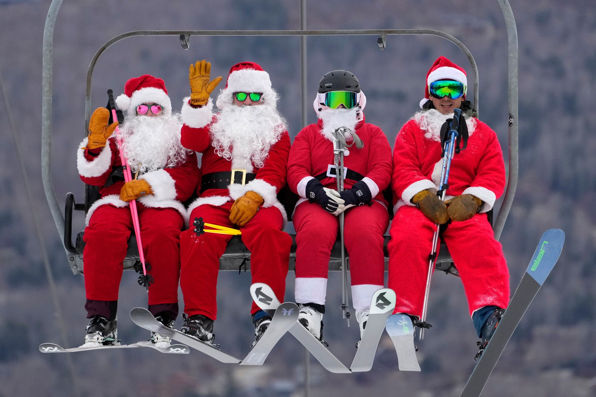 Skiers dressed in Santa Claus outfits ride a chairlift at the Sunday River Ski Resort in Newry, Maine